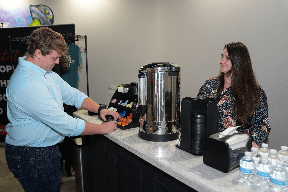 woman serving coffee to man in blue shirt